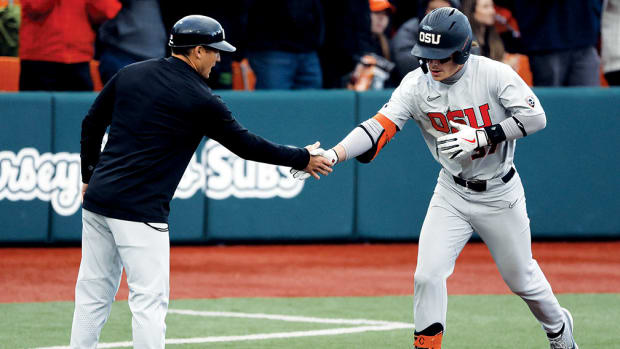 Oregon State Beavers infielder Travis Bazzana congratulated by third base coach Ryan Gipson for a home run.